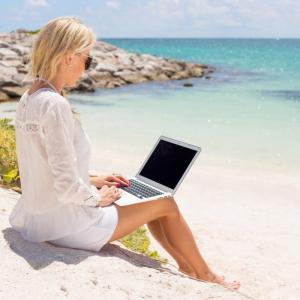 Businesswoman working with computer on the beach Businesswoman working with laptop computer on the beach.