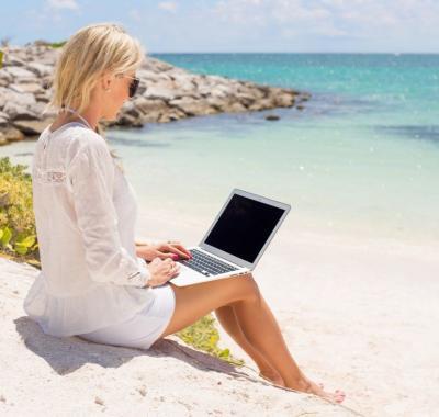 Businesswoman working with computer on the beach Businesswoman working with laptop computer on the beach.