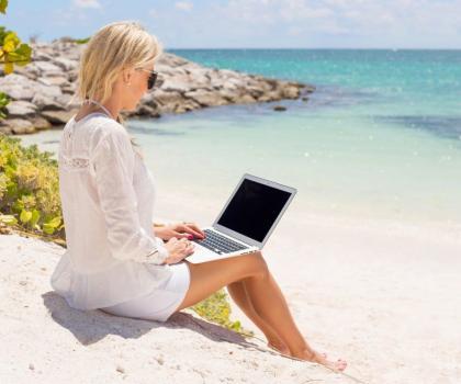 Businesswoman working with computer on the beach Businesswoman working with laptop computer on the beach.