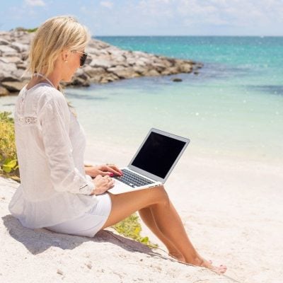 Businesswoman working with laptop computer on the beach.